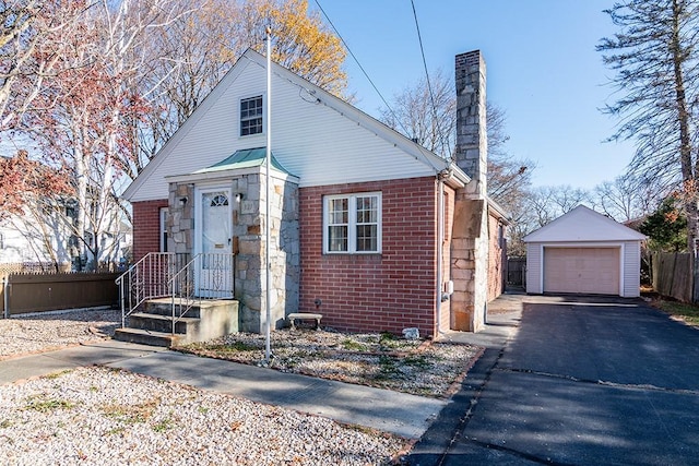 bungalow featuring an outdoor structure, a chimney, brick siding, driveway, and a detached garage