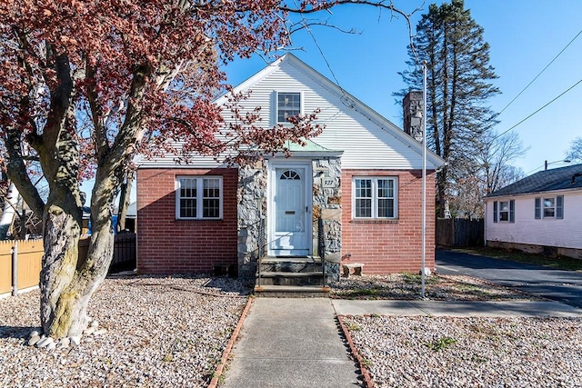 bungalow-style house with brick siding, fence, and a chimney