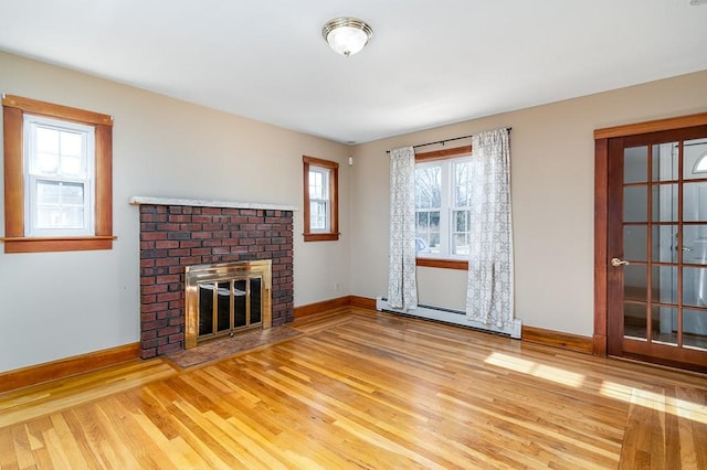 unfurnished living room with baseboards, a baseboard heating unit, wood finished floors, and a brick fireplace