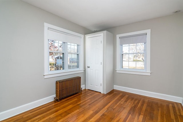 unfurnished bedroom with radiator, baseboards, and wood finished floors