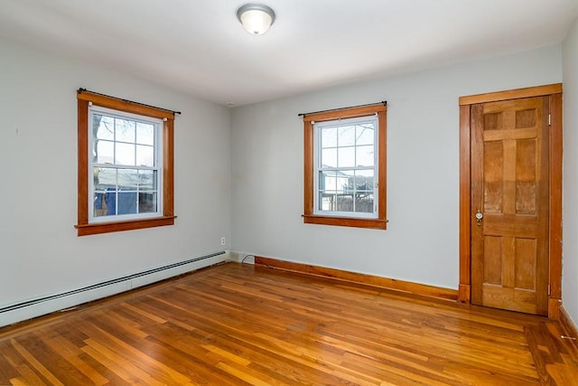 empty room with baseboards, baseboard heating, and wood finished floors