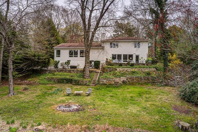 back of property with a yard and an outdoor fire pit