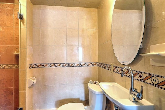 bathroom featuring a sink, toilet, and tile walls