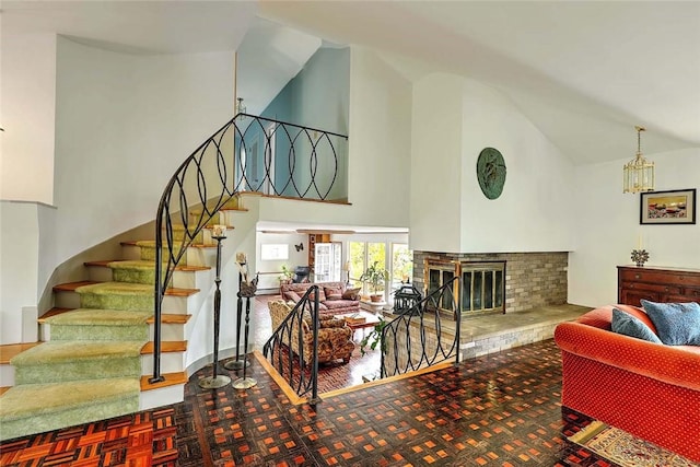 living room with a brick fireplace, high vaulted ceiling, and stairway