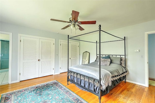 bedroom featuring baseboards, a ceiling fan, wood finished floors, and two closets