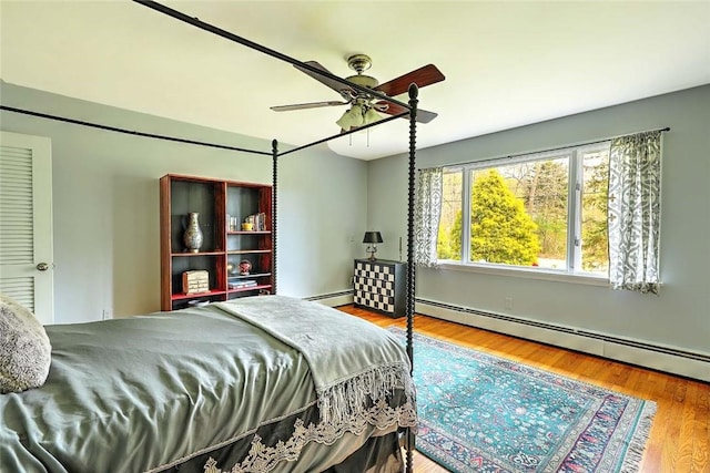 bedroom with baseboards, ceiling fan, wood finished floors, and a baseboard radiator
