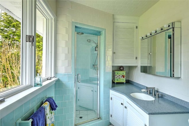 bathroom with vanity, tile walls, and a shower stall