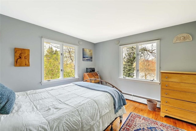 bedroom featuring wood finished floors and a baseboard radiator