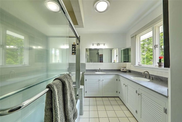 full bathroom with a sink, tile patterned flooring, double vanity, tile walls, and an enclosed shower