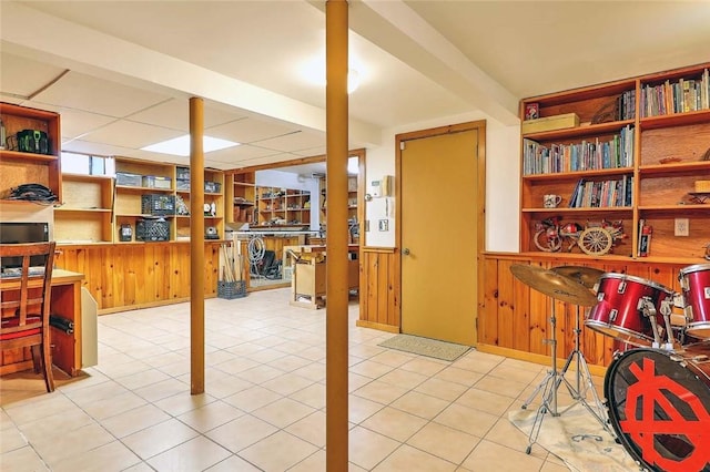 finished basement featuring a wainscoted wall, tile patterned flooring, and wood walls