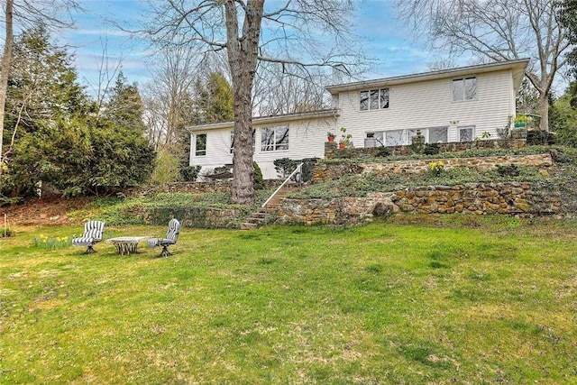 rear view of house featuring a lawn and stairs