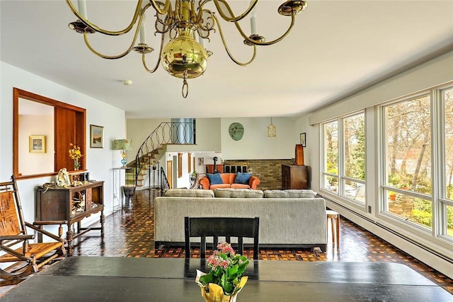 living room with plenty of natural light, a chandelier, baseboard heating, and stairway