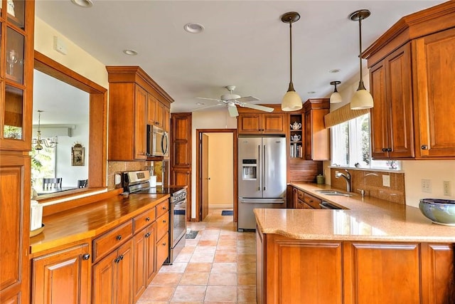 kitchen with brown cabinetry, a ceiling fan, a sink, backsplash, and stainless steel appliances