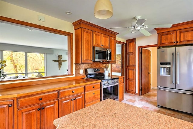 kitchen featuring decorative backsplash, ceiling fan, appliances with stainless steel finishes, light countertops, and light tile patterned floors