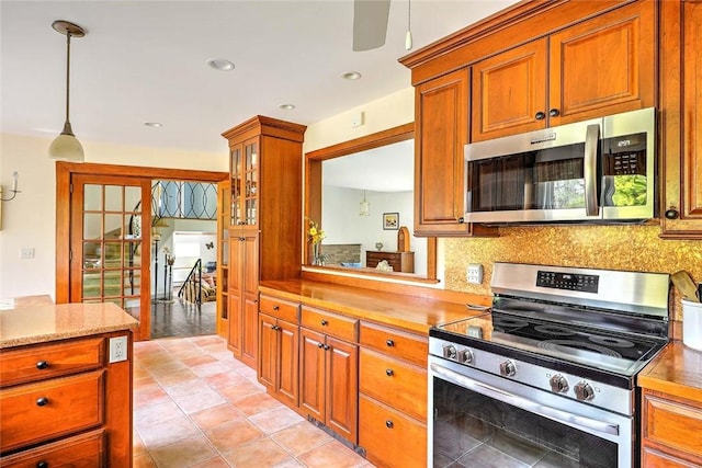 kitchen featuring light countertops, brown cabinets, backsplash, hanging light fixtures, and stainless steel appliances