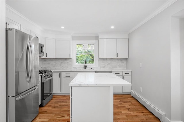 kitchen with a kitchen island, appliances with stainless steel finishes, a sink, a baseboard heating unit, and light wood finished floors