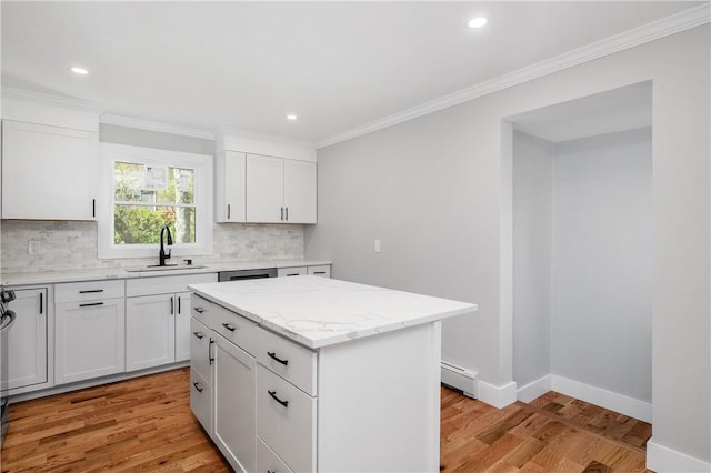 kitchen with baseboard heating, a sink, light wood-style flooring, tasteful backsplash, and ornamental molding