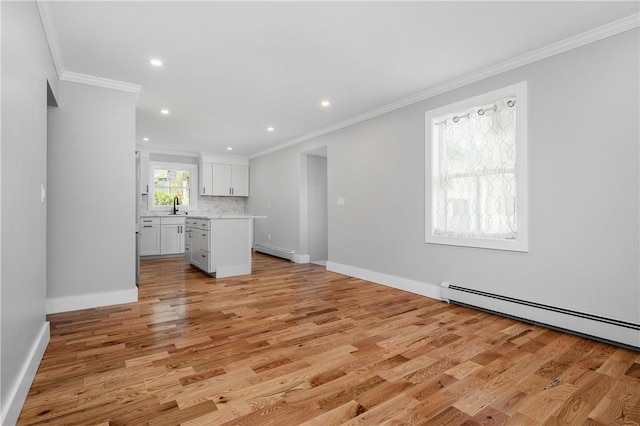 unfurnished living room featuring crown molding, baseboard heating, light wood-type flooring, a sink, and baseboards