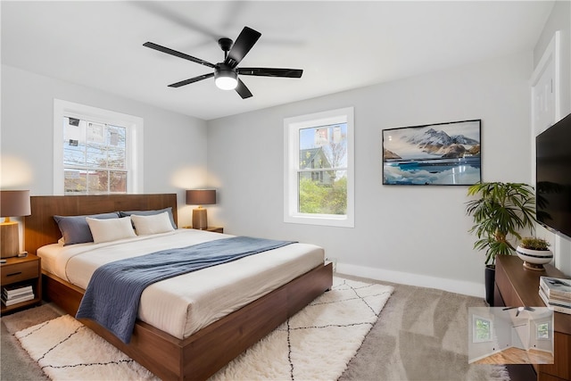 carpeted bedroom with baseboards, multiple windows, and ceiling fan