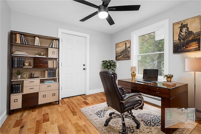 home office featuring a ceiling fan, baseboards, a baseboard heating unit, and light wood-type flooring