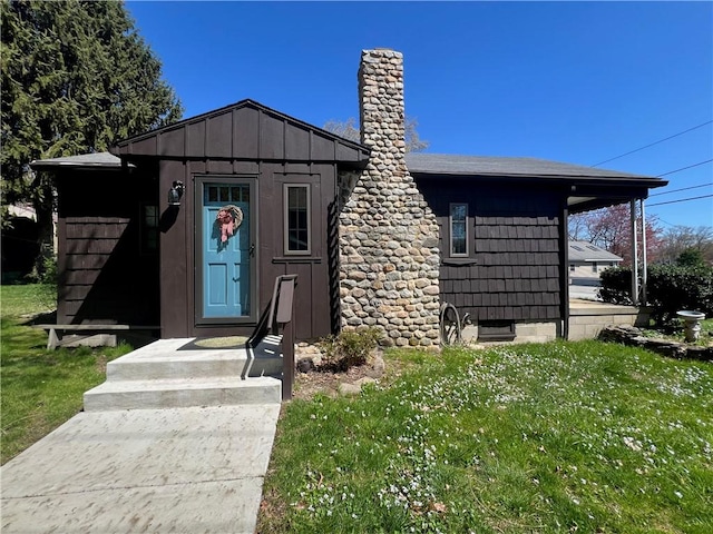 view of front facade featuring board and batten siding, a chimney, and a front yard