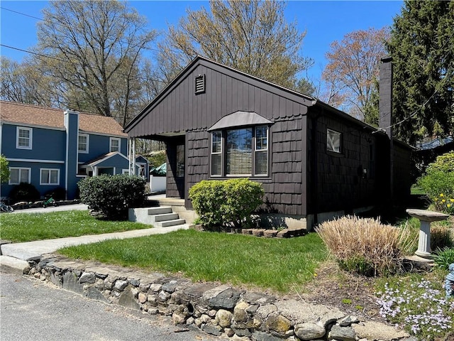 bungalow-style house with a chimney and a front yard