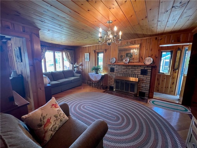 living area with an inviting chandelier, wood walls, a brick fireplace, wood finished floors, and wood ceiling