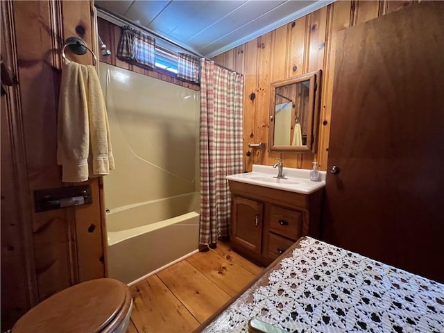 bathroom with vanity, wood finished floors, toilet, shower / bathtub combination with curtain, and wooden walls