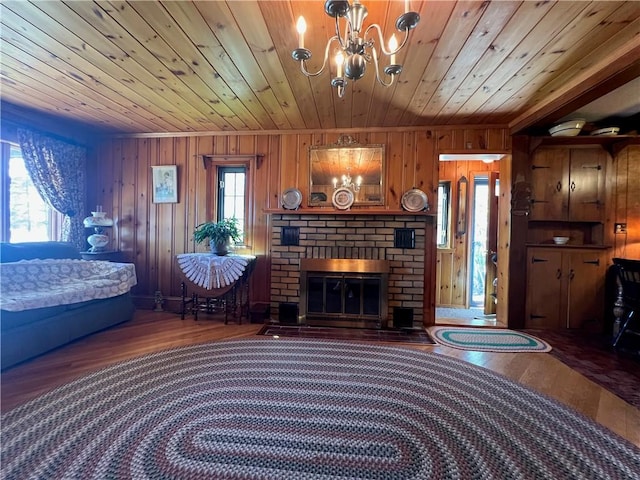 living room with a notable chandelier, wood walls, wooden ceiling, and wood finished floors