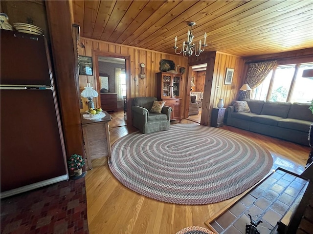 living area featuring an inviting chandelier, wood ceiling, wood finished floors, and wooden walls