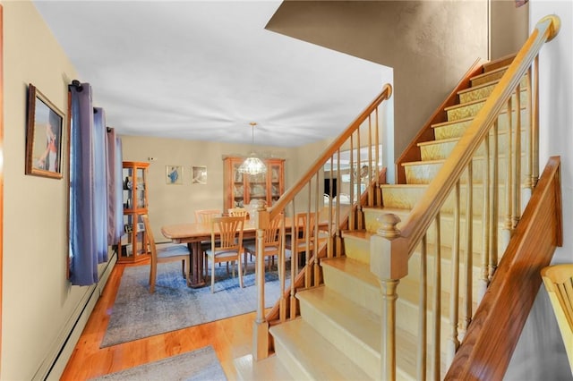 dining room with a baseboard heating unit, stairs, and wood finished floors