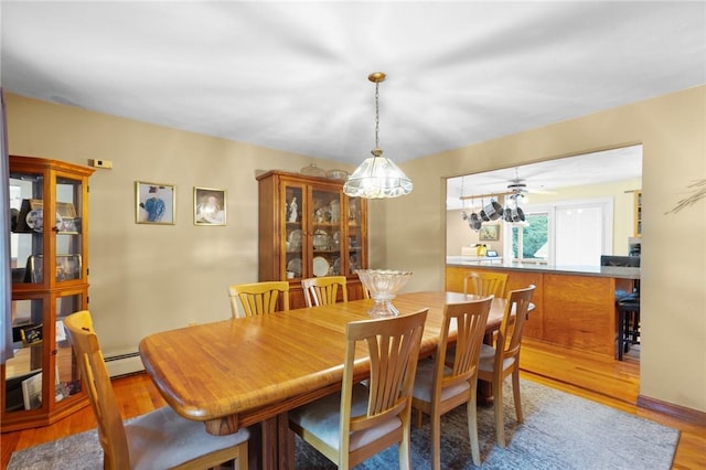 dining room with a baseboard radiator, a ceiling fan, and wood finished floors