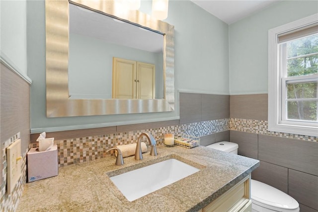 bathroom featuring vanity, toilet, and tile walls