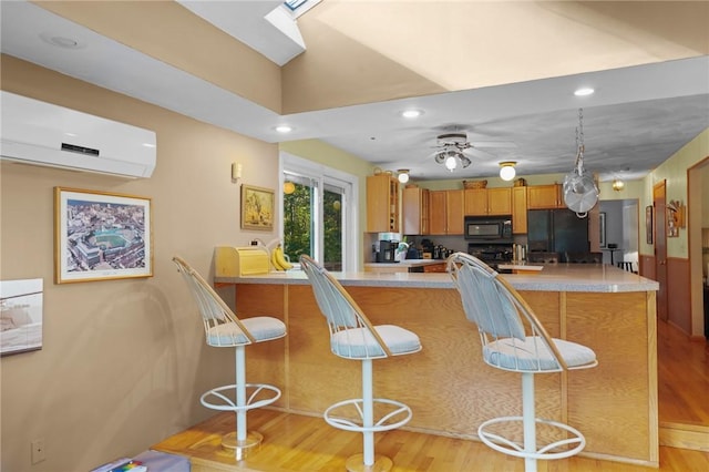 kitchen featuring recessed lighting, light countertops, a wall unit AC, and black appliances