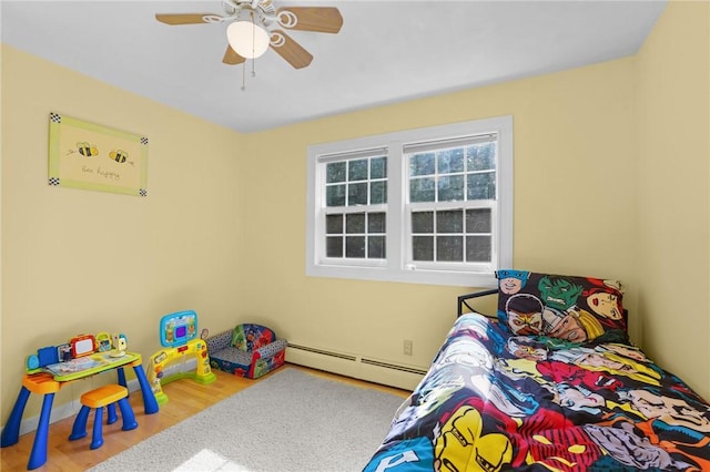 bedroom featuring a ceiling fan, wood finished floors, and baseboard heating