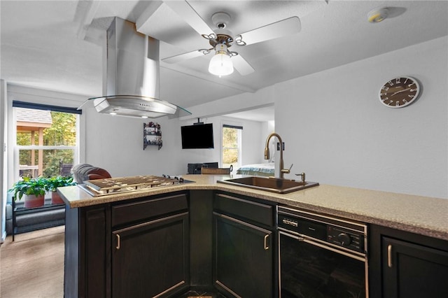 kitchen featuring stainless steel gas cooktop, a wealth of natural light, a sink, and wall chimney range hood