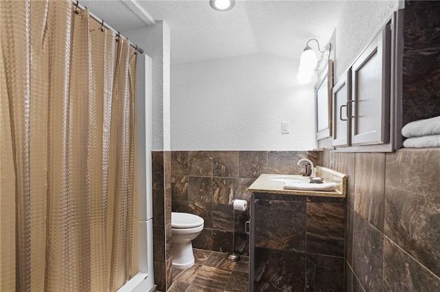 full bathroom featuring vanity, toilet, a textured ceiling, tile walls, and curtained shower