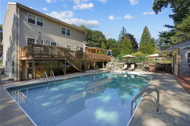 pool with stairs, a patio area, a wooden deck, and fence