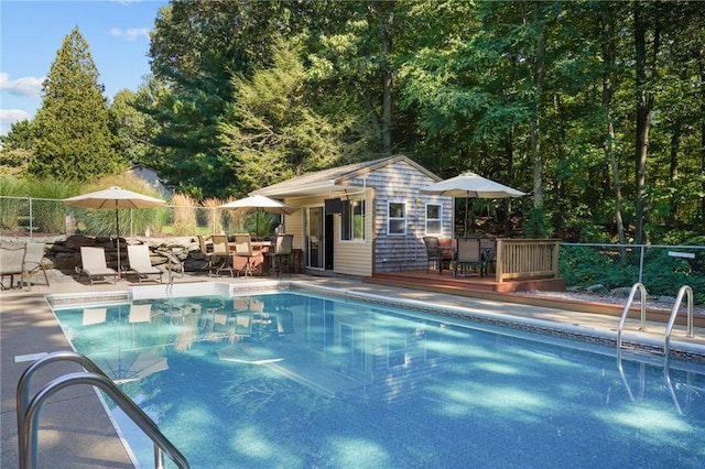 pool featuring a patio area, a storage structure, an outbuilding, and fence