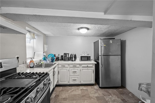 752 Social St, Woonsocket, RI 02895 - kitchen with a textured ceiling, a sink, light countertops, white cabinets, and stainless steel appliances