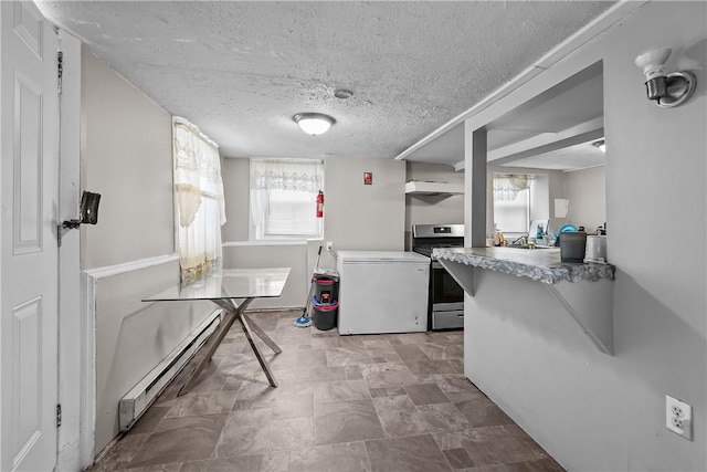 752 Social St, Woonsocket, RI 02895 - kitchen featuring a textured ceiling, stainless steel range with gas stovetop, fridge, a baseboard heating unit, and a wealth of natural light