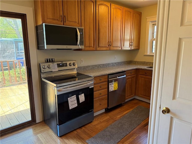 kitchen with brown cabinetry, light wood-style flooring, and appliances with stainless steel finishes