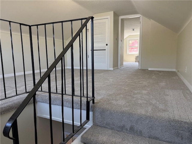 stairway with carpet flooring, baseboards, and vaulted ceiling