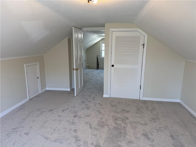 bonus room featuring carpet floors, baseboards, a textured ceiling, and lofted ceiling