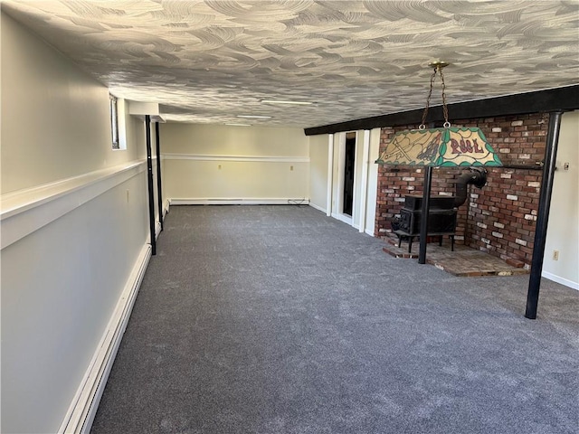 finished below grade area featuring baseboards, a baseboard heating unit, dark carpet, and a wood stove