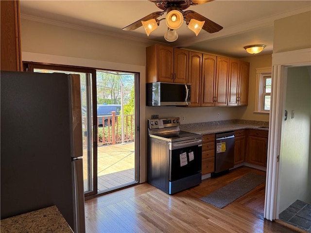 kitchen with crown molding, appliances with stainless steel finishes, brown cabinets, and light wood-style flooring