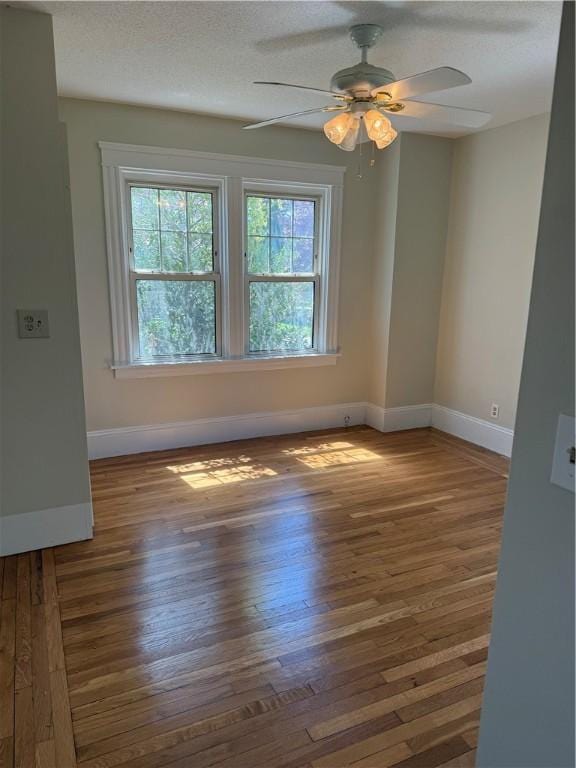 unfurnished room with a ceiling fan, baseboards, and wood finished floors