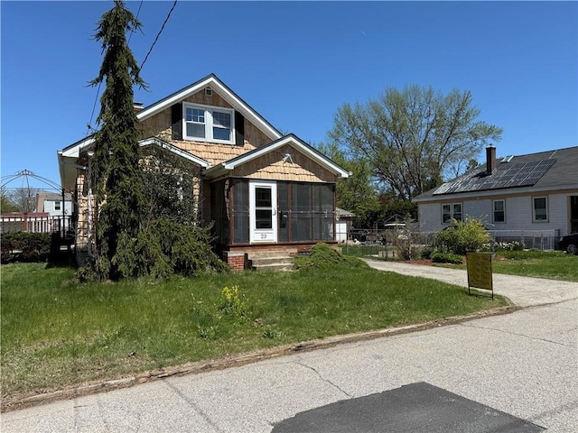 view of front of property featuring a front yard and a sunroom