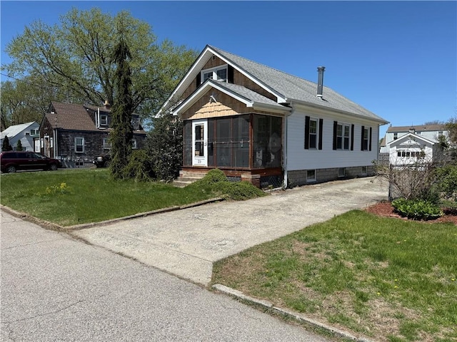 view of front of house featuring a sunroom, driveway, and a front yard