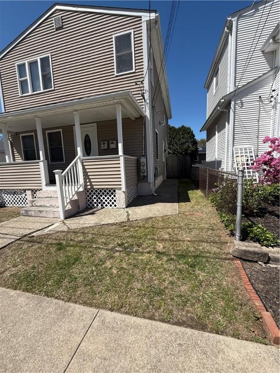 view of front of home with a porch, fence, and a front yard